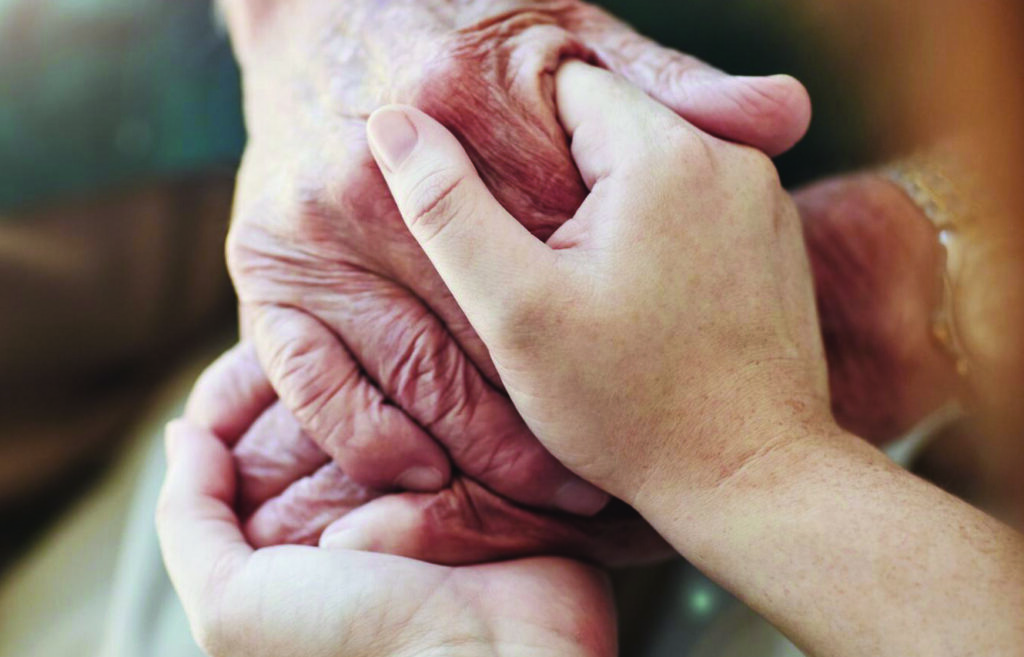 An image of a woman and senior man holding hands.