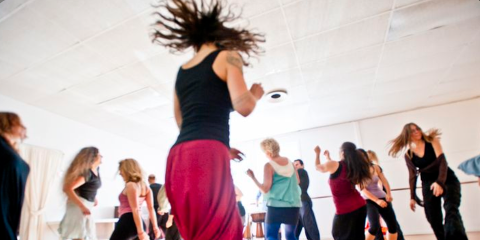 Dance instructor moving quickly while teaching a class of people.