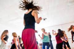 Dance instructor moving quickly while teaching a class of people.