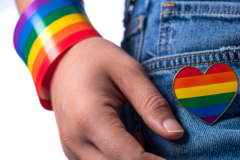close up of person's hand with rainbow bracelet and rainbow heart on jeans pocket
